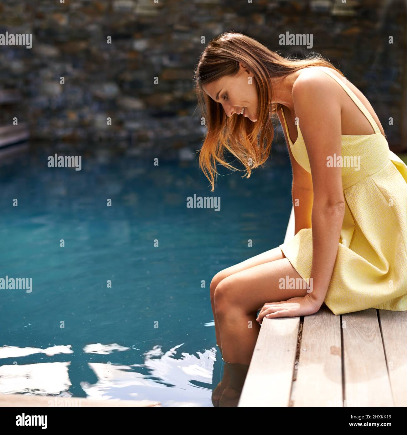 Piaceri semplici presso la piscina. Bella donna in un abito giallo in piscina. Foto Stock