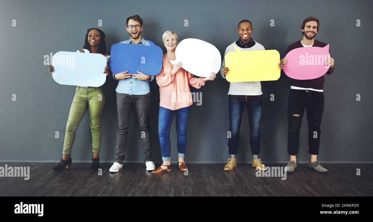 Parla la tua mente. Studio girato di un gruppo diversificato di persone che tengono in su bolle di discorso su uno sfondo grigio. Foto Stock