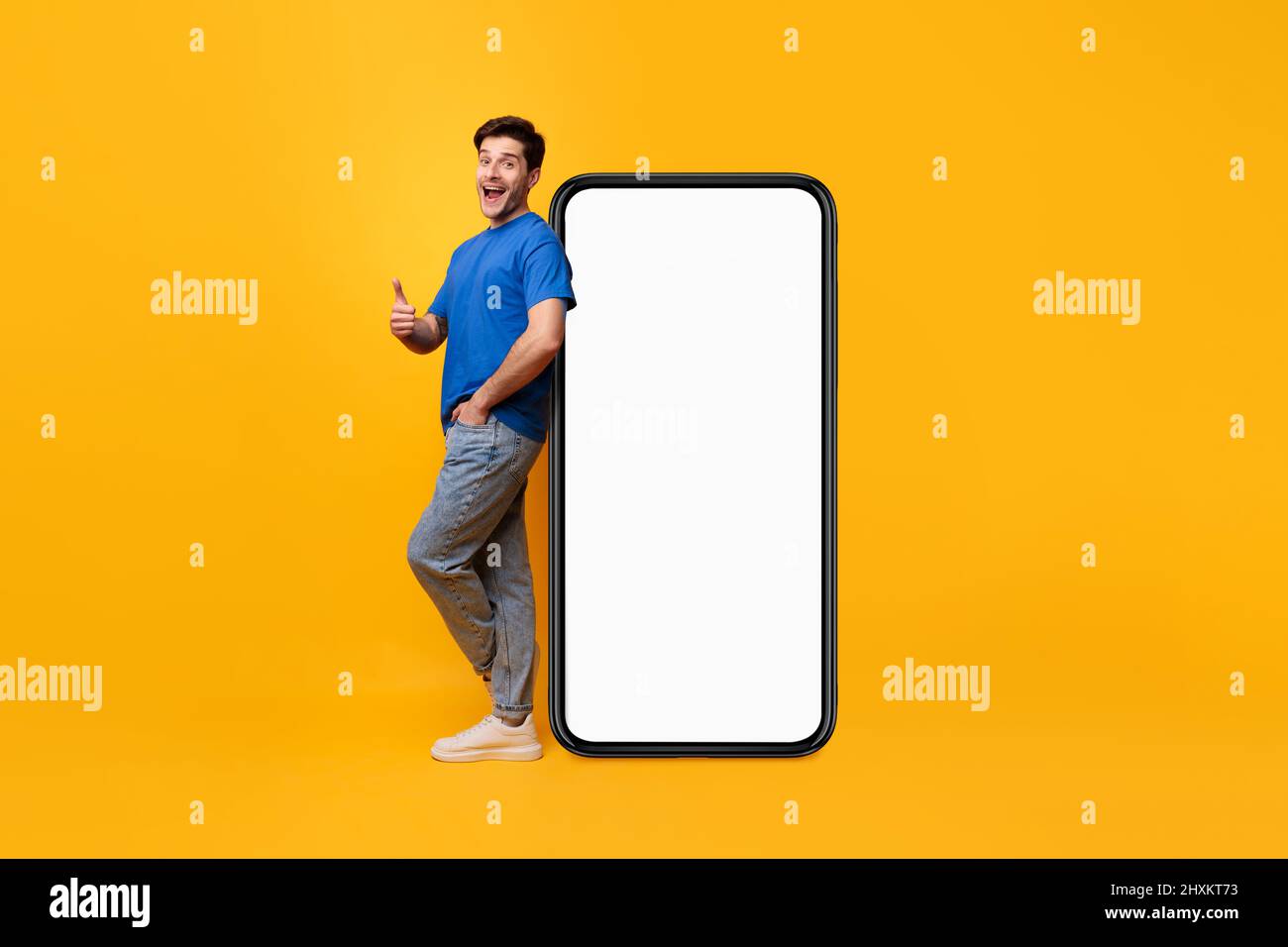 Uomo appoggiato sullo schermo bianco dello smartphone che mostra i pollici verso l'alto Foto Stock