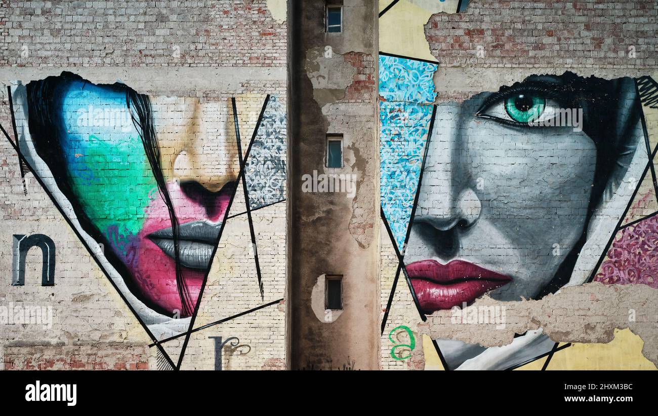 Facciata di una vecchia casa in mattoni con un dipinto del volto di una donna Foto Stock