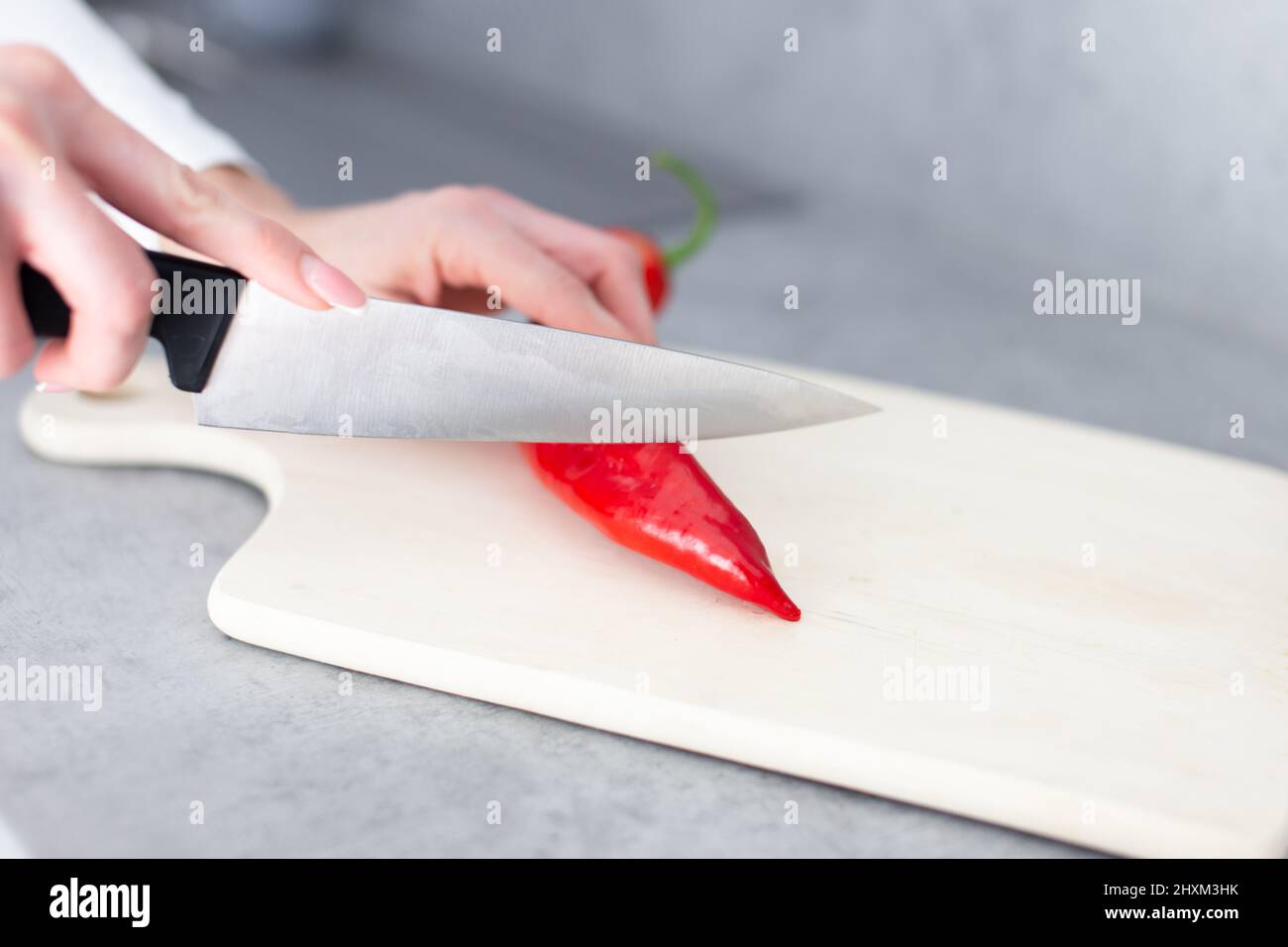 Donna taglio a mano rosso peperoncino caldo in cucina Foto Stock