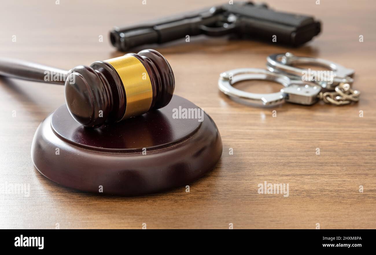 Giudice Gavel e pistola sul banco ufficio avvocato. Crimine, concetto di punizione dell'omicidio. Tavolo del tribunale in legno, vista ravvicinata Foto Stock