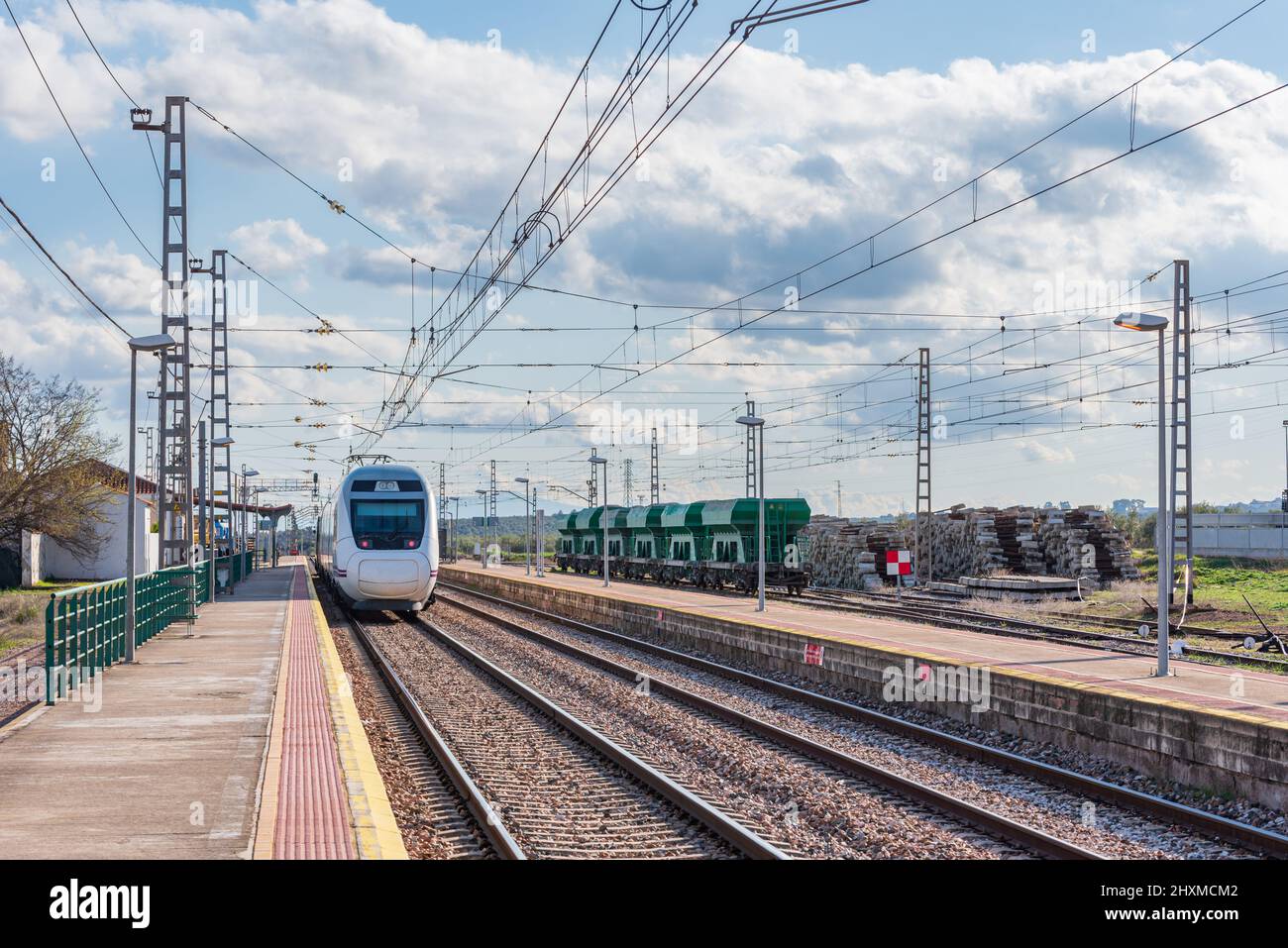 Treno passeggeri elettrico in attesa accanto alla piattaforma, di fronte ad alcune vetture da carico. Foto Stock