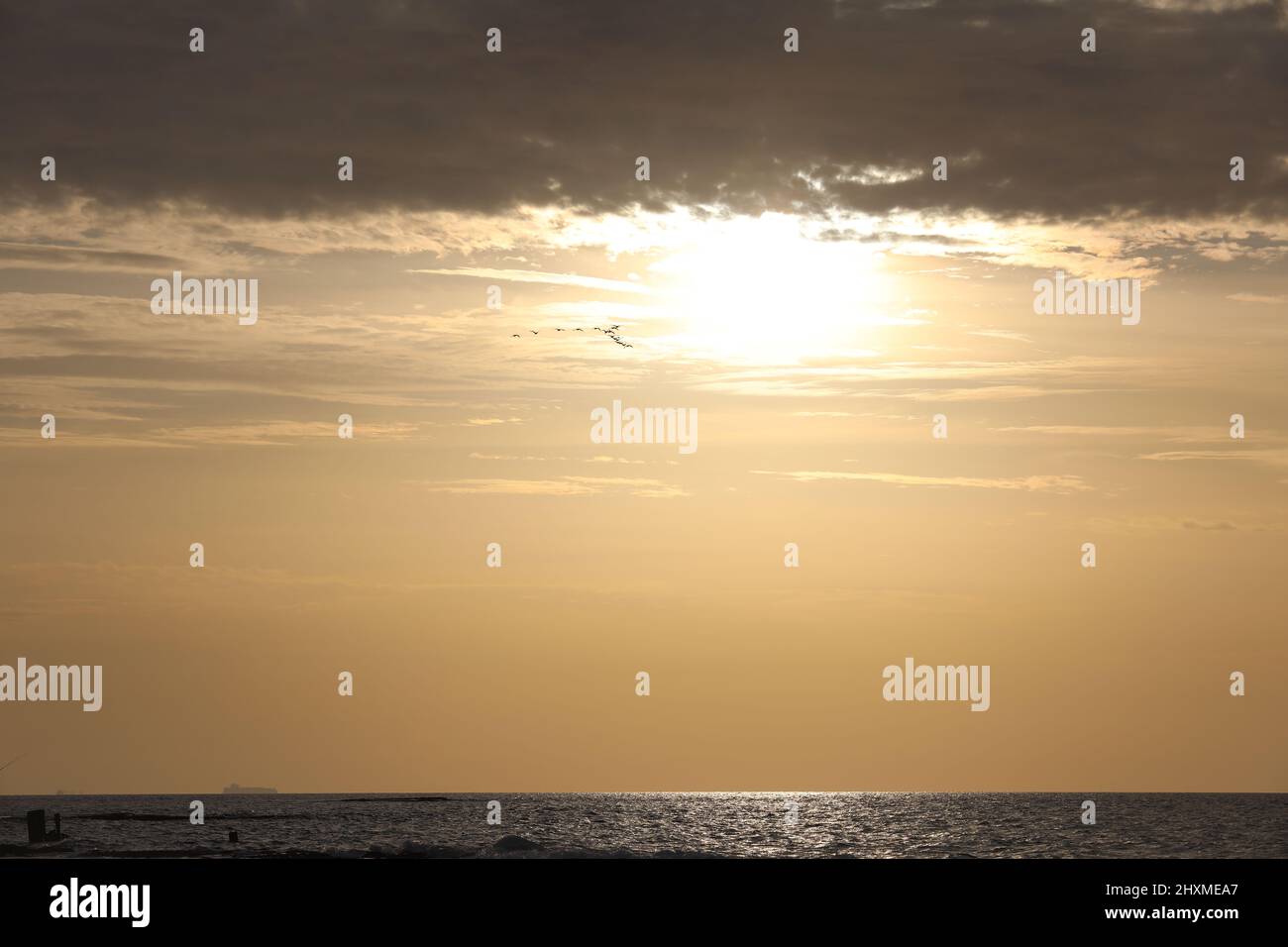 Il tramonto e le luci del sole si tramonta tra le nuvole e l'oceano Foto Stock
