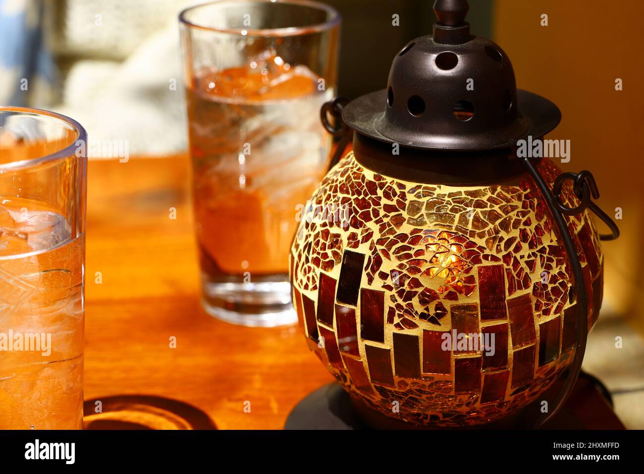 Lanterne tonde in vetro a mosaico e due bicchieri allineati sul tavolo Foto Stock