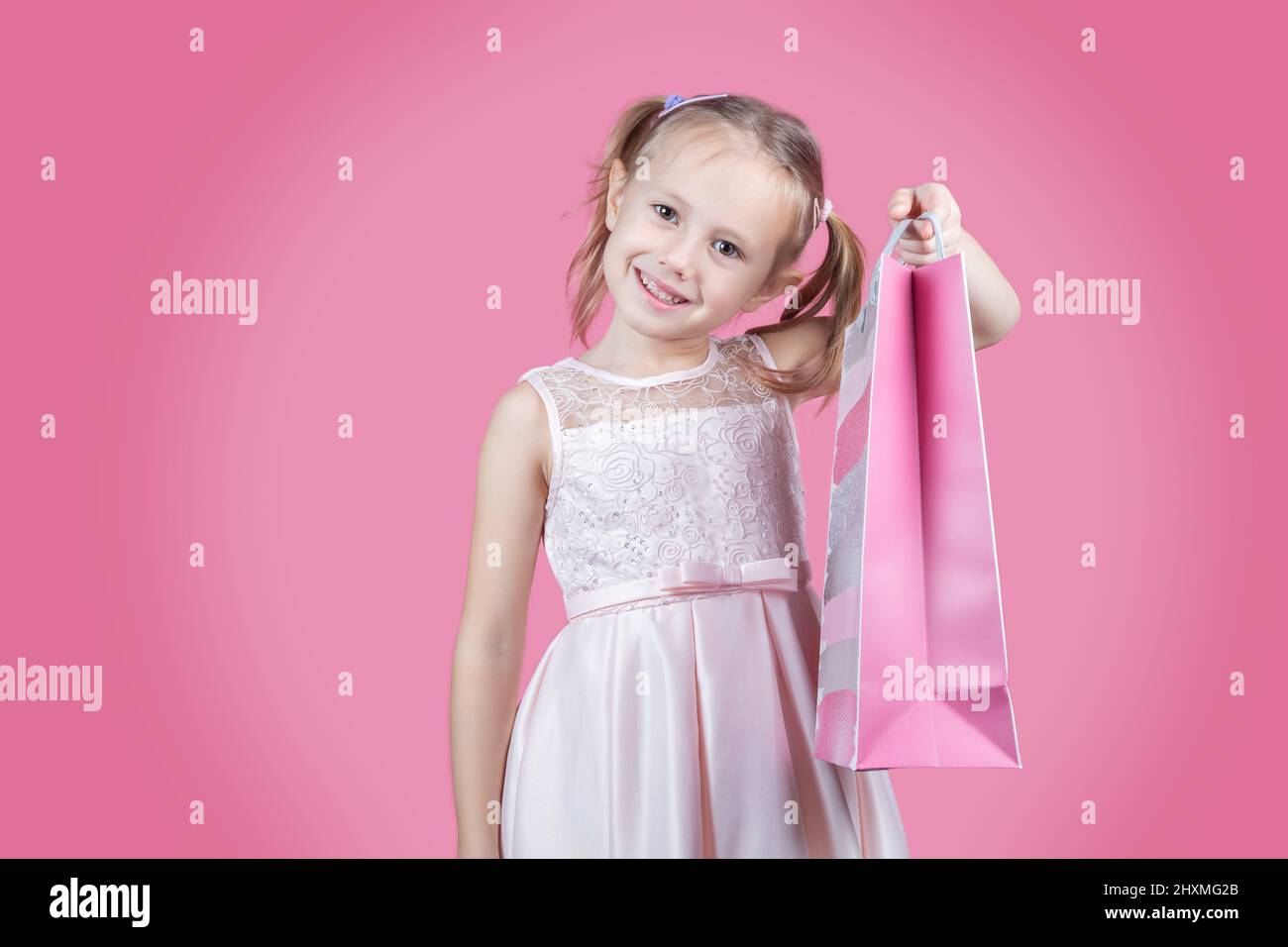 Ritratto della ragazza caucasica positiva hanno divertimento sul tempo libero tenendo i sacchetti colorati addicted le occasioni dello shopper sopra sfondo rosa del colore con spazio della copia. Foto Stock