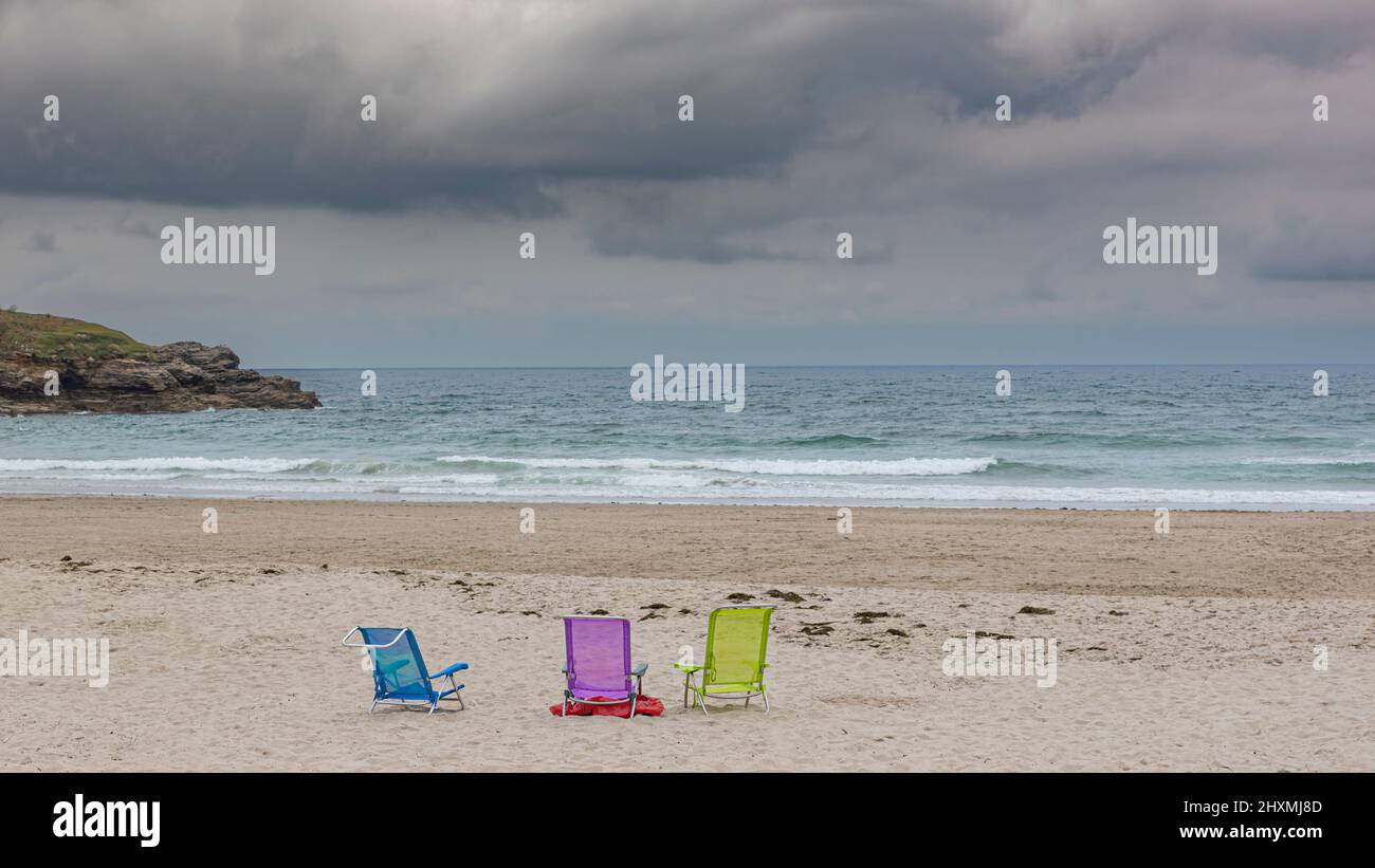 Sedie da spiaggia sulla sabbia senza nessuno in mauve, giallo e blu verdastro Foto Stock