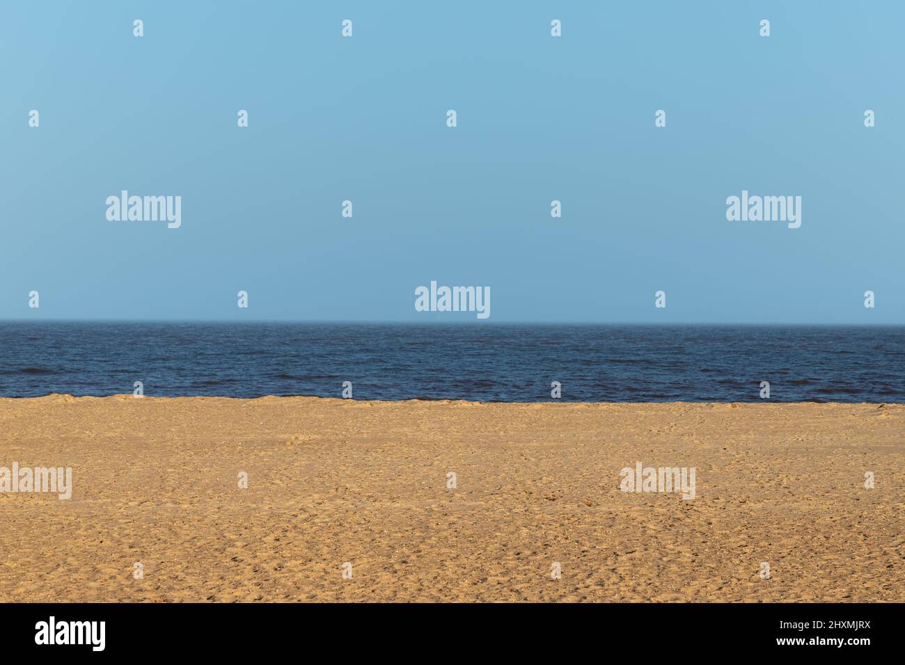 Immagine minimalista di Grreat Yarmouth Beach con la sabbia, l'acqua e il cielo blu in un pomeriggio di marzo soleggiato Foto Stock