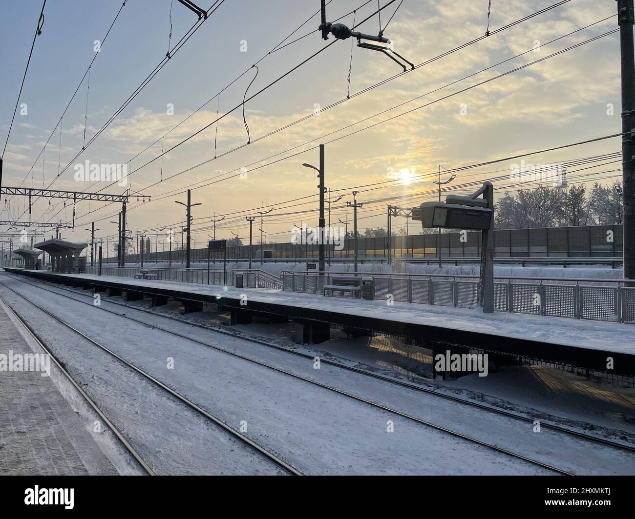 Piattaforma ferroviaria vuota senza passeggeri in inverno al tramonto. Ferrovia, concetto di clima freddo, fuoco selettivo e softfocus Foto Stock