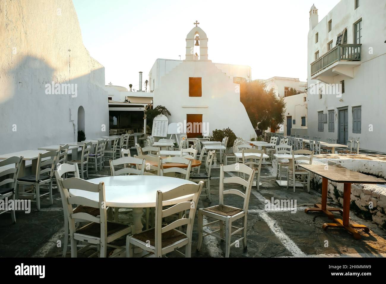 Street cafè tavoli con tradizionali case imbiancate a calce nell'isola di Mykonos, in Grecia Foto Stock