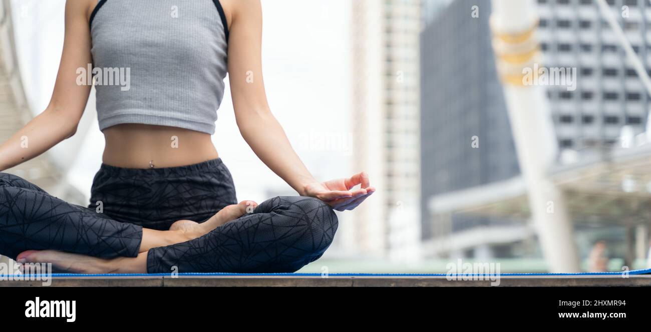 Mani ravvicinate. Donna fa yoga all'aperto in città. Donna che esercita vitale e meditazione per lo stile di vita fitness all'aperto in background città. Sano Foto Stock