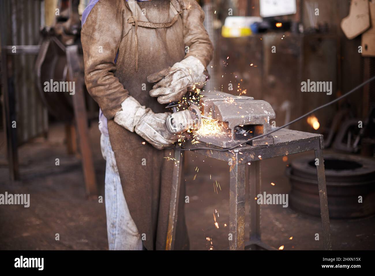 Fare la magia accadere. Un uomo che macina il metallo in un'officina. Foto Stock