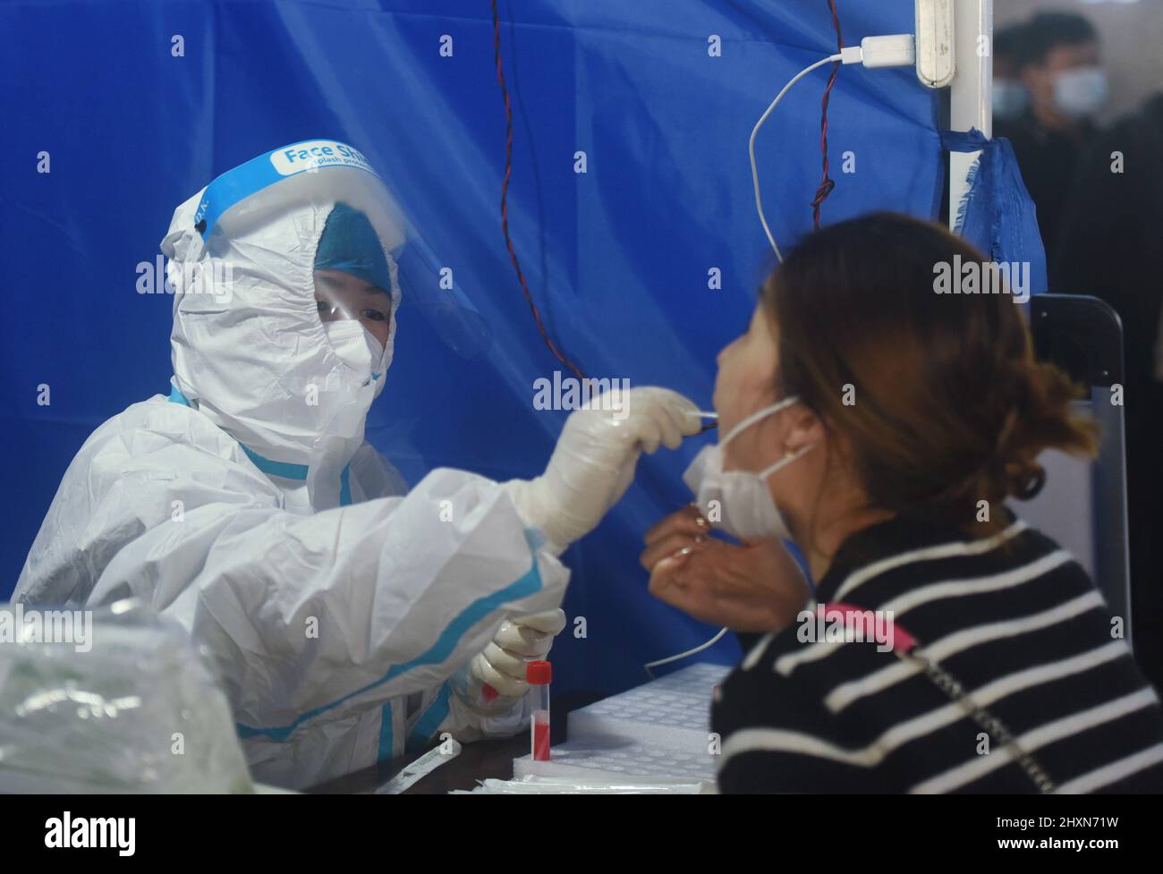 HANGZHOU, CINA - 14 MARZO 2022 - Un operatore medico preleva campioni di acido nucleico per i passeggeri in un punto di test temporaneo per gli acidi nucleici a Hangzhou Ra Foto Stock