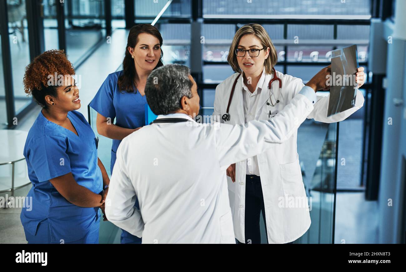 La salute del paziente è uno sforzo di squadra. Shot di un team di medici che discutono i risultati di una radiografia in un ospedale. Foto Stock