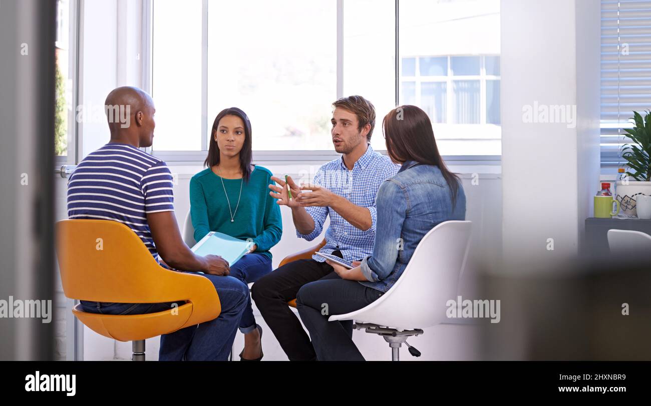 Ottenere le sue idee attraverso. Scatto di un giovane gruppo di progettisti che hanno una discussione. Foto Stock