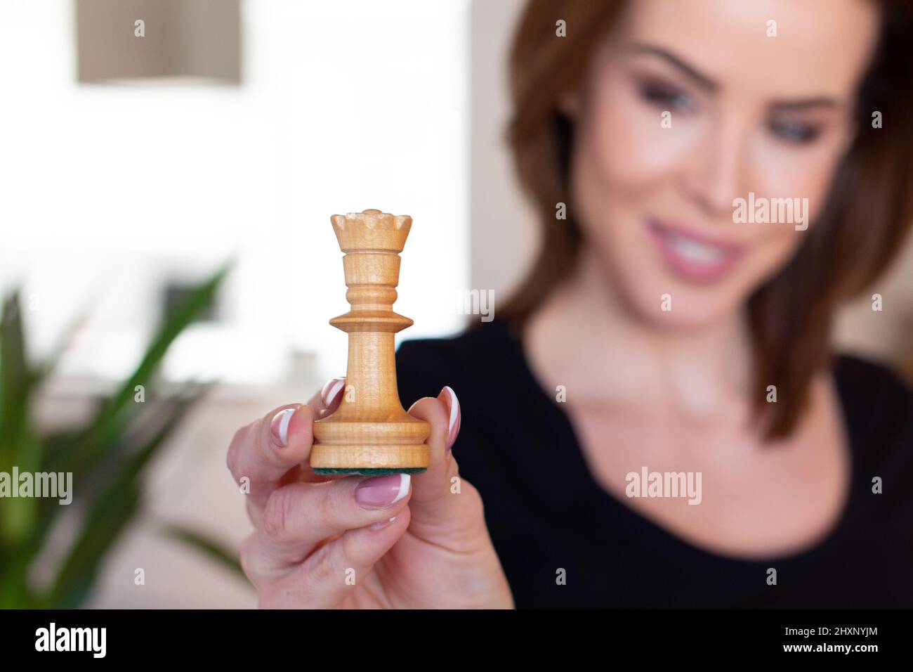 Giovane donna fiduciosa che tiene la regina degli scacchi, profondità di campo Foto Stock
