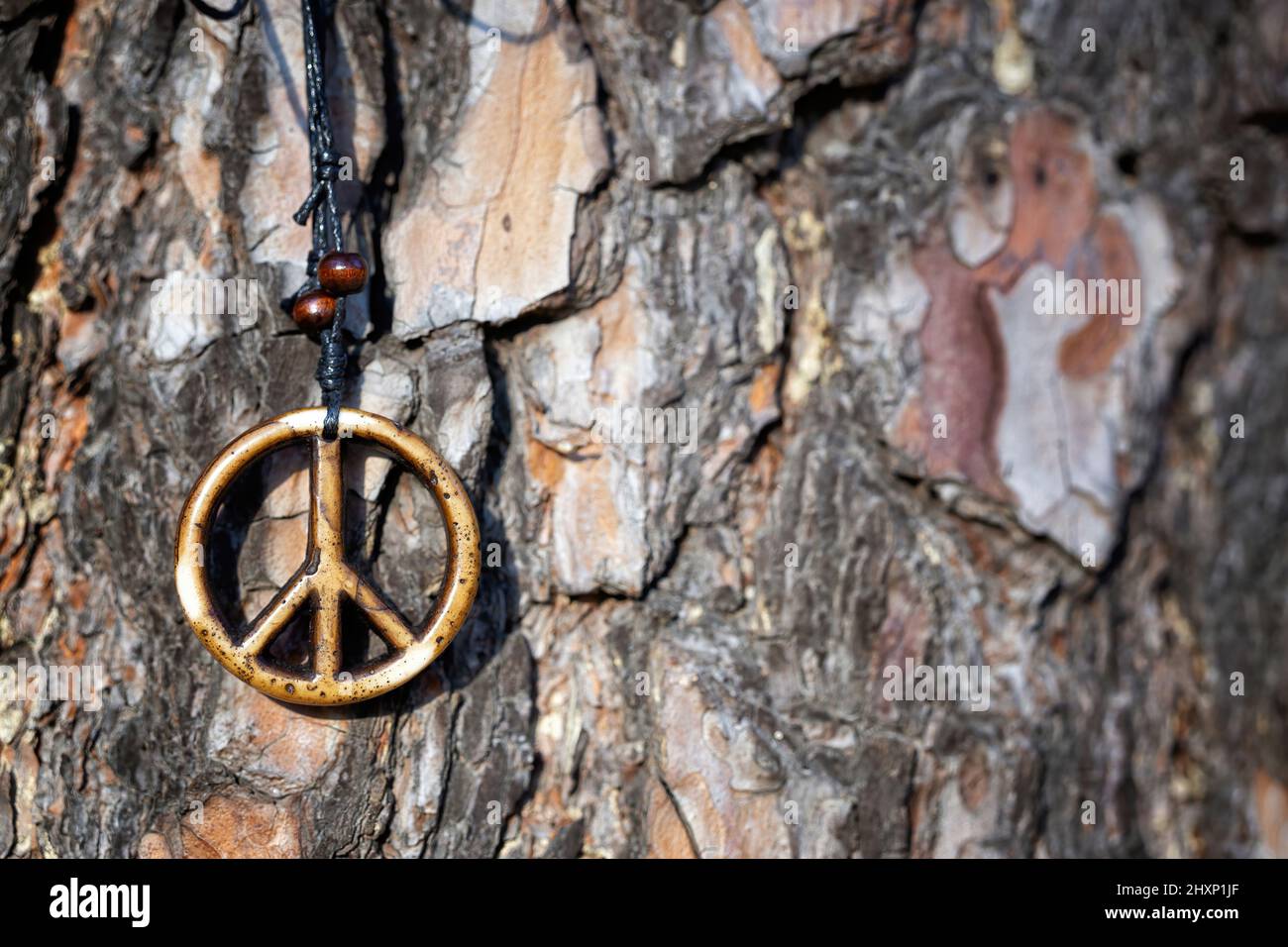 Collana di segno di pace in legno contro una corteccia del tronco dell'albero, spazio di copia Foto Stock