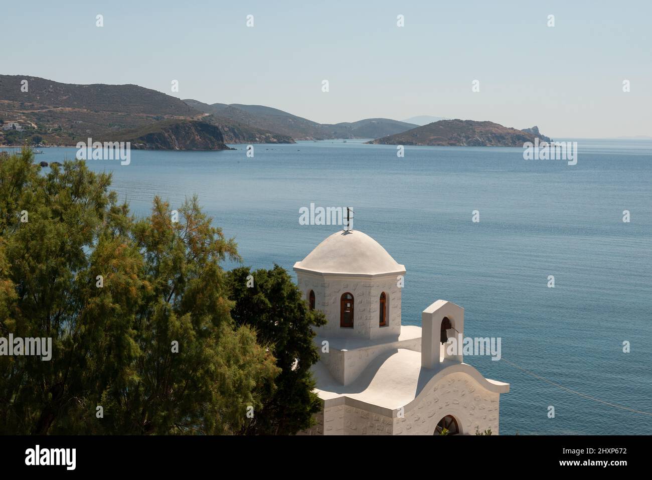 Linea costiera di Paralia Campos nelle giornate di sole con chiesa greca e albero in primo piano Foto Stock