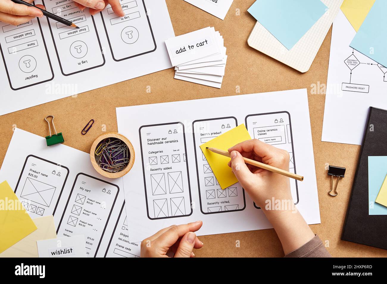 Due web designer che lavorano insieme su un sito web mobile reattivo. Immagine piatta di numerosi schizzi di strutture a reticolo di app sulla scrivania dei progettisti di prodotti. Foto Stock