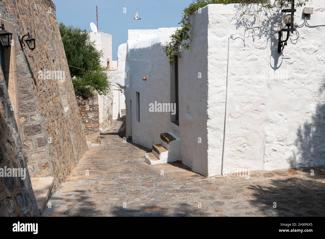 Vicolo stretto in Chora dell'isola di Patmos con pareti bianche, scale e cielo blu Foto Stock