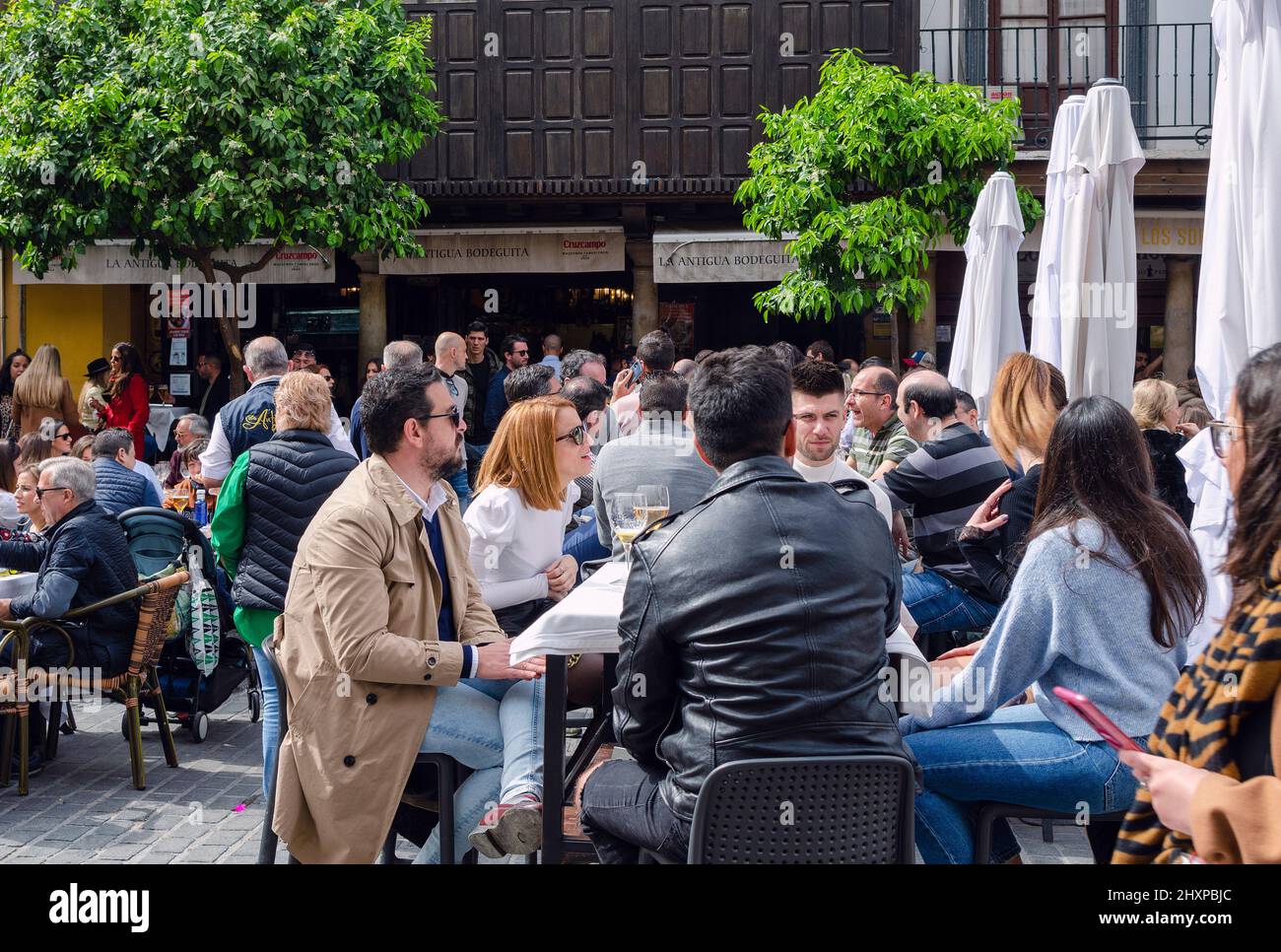 Siviglia, Spagna; 12 marzo 2022: Persone che parlano, bevono e godono di una bella giornata di sole in una terrazza di Piazza Salvador (Plaza del Salvador) Foto Stock