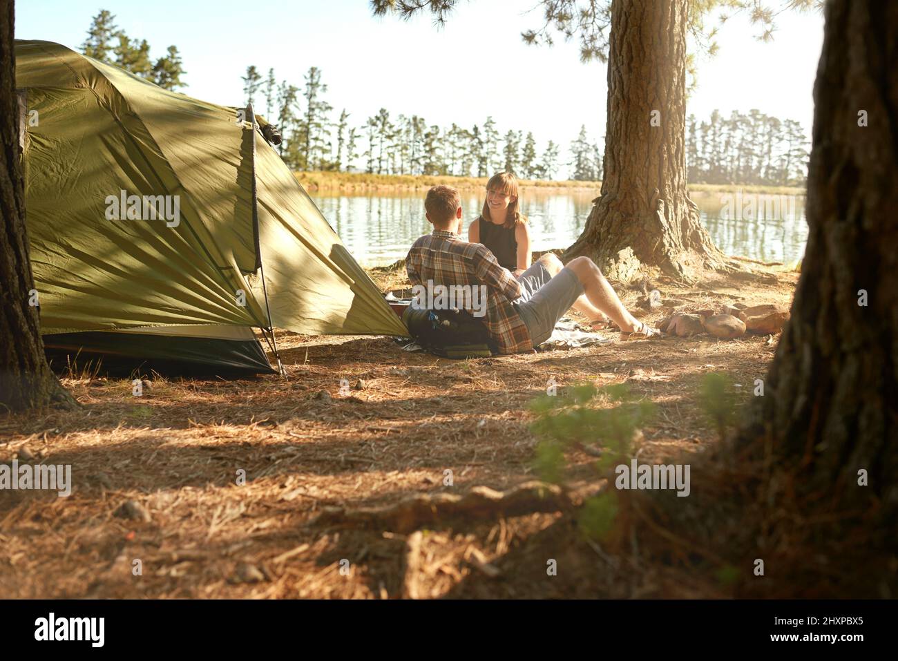 Nei boschi. Scatto di una giovane coppia campeggio vicino ad un lago. Foto Stock