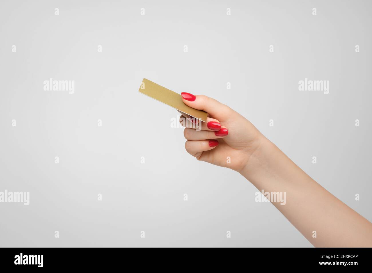 Carta di credito o debito in oro di plastica in mano di una donna, smalto rosso unghie Foto Stock