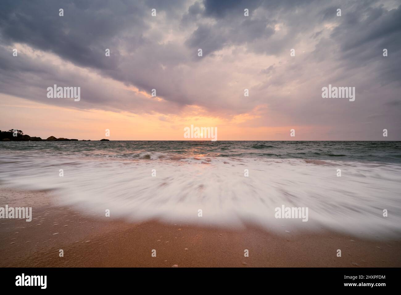 Bellissimo tramonto sull'Oceano Indiano. Lunga esposizione di onde di mare su spiaggia di sabbia vuota in Sri Lanka. Foto Stock