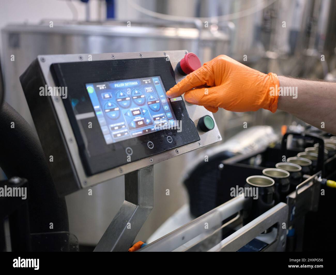 Mano di un lavoratore che tocca lo schermo di una macchina elettronica di un birrificio Foto Stock
