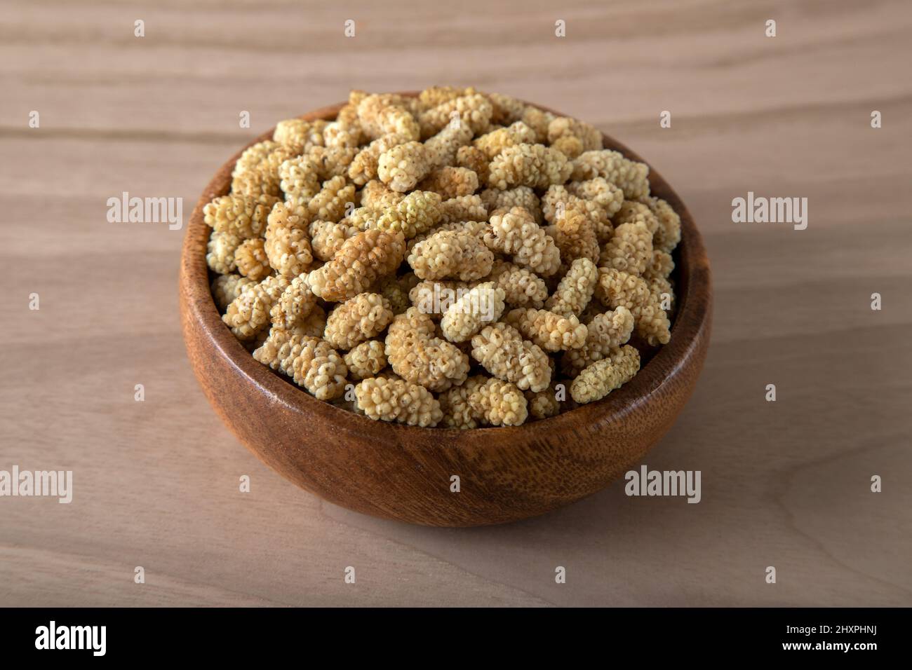 Ciotola piena di gelso secco su sfondo di legno Foto Stock
