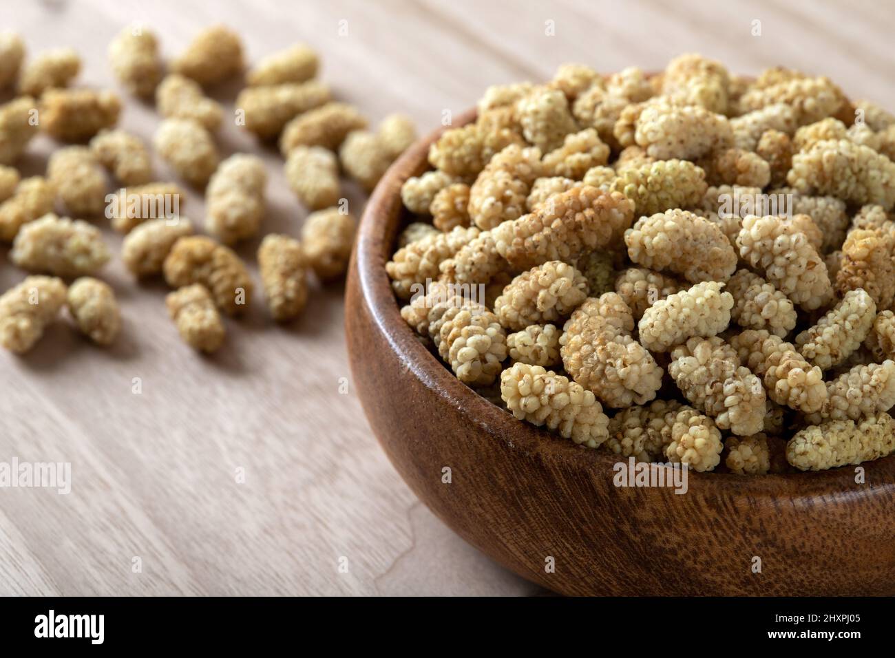 Ciotola piena di gelso secco su sfondo di legno Foto Stock