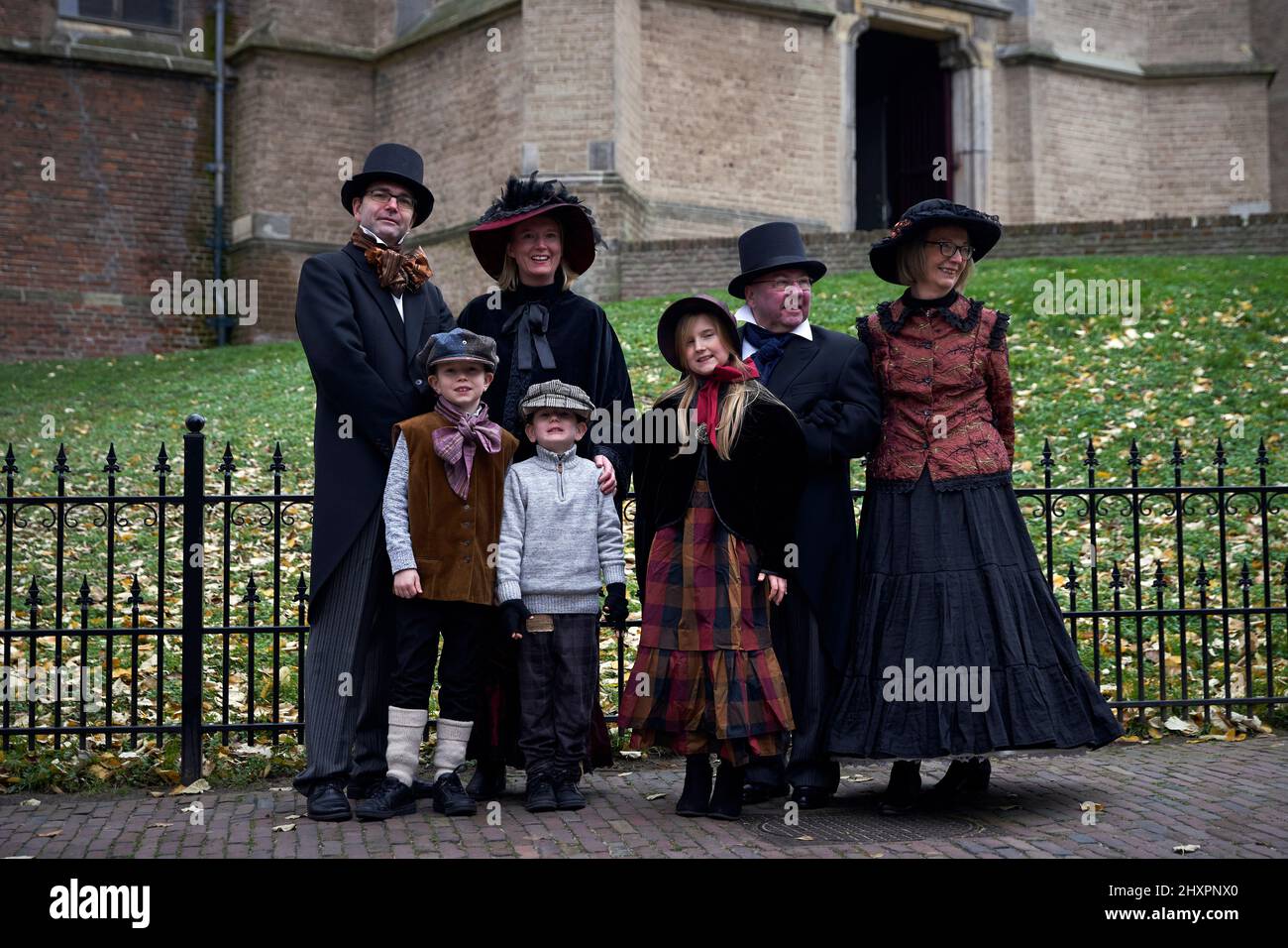 Una famiglia vestita con abiti d'epoca posa per fotografi accanto alla chiesa della città Foto Stock