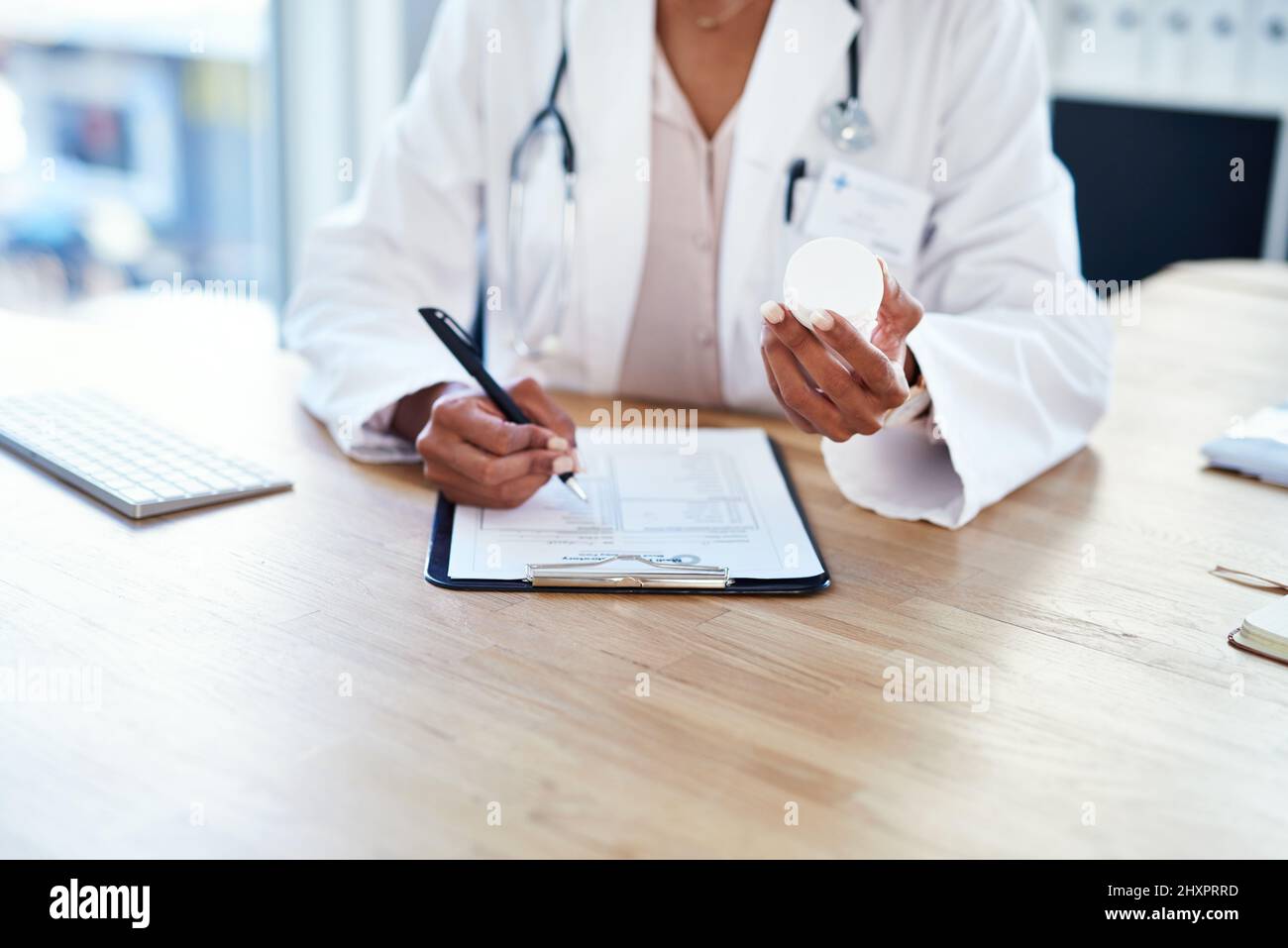 Invia i suoi pazienti a casa ben attrezzati per il recupero. Shot di un medico giovane che compila un modulo per una prescrizione nella sua stanza di consulenza. Foto Stock