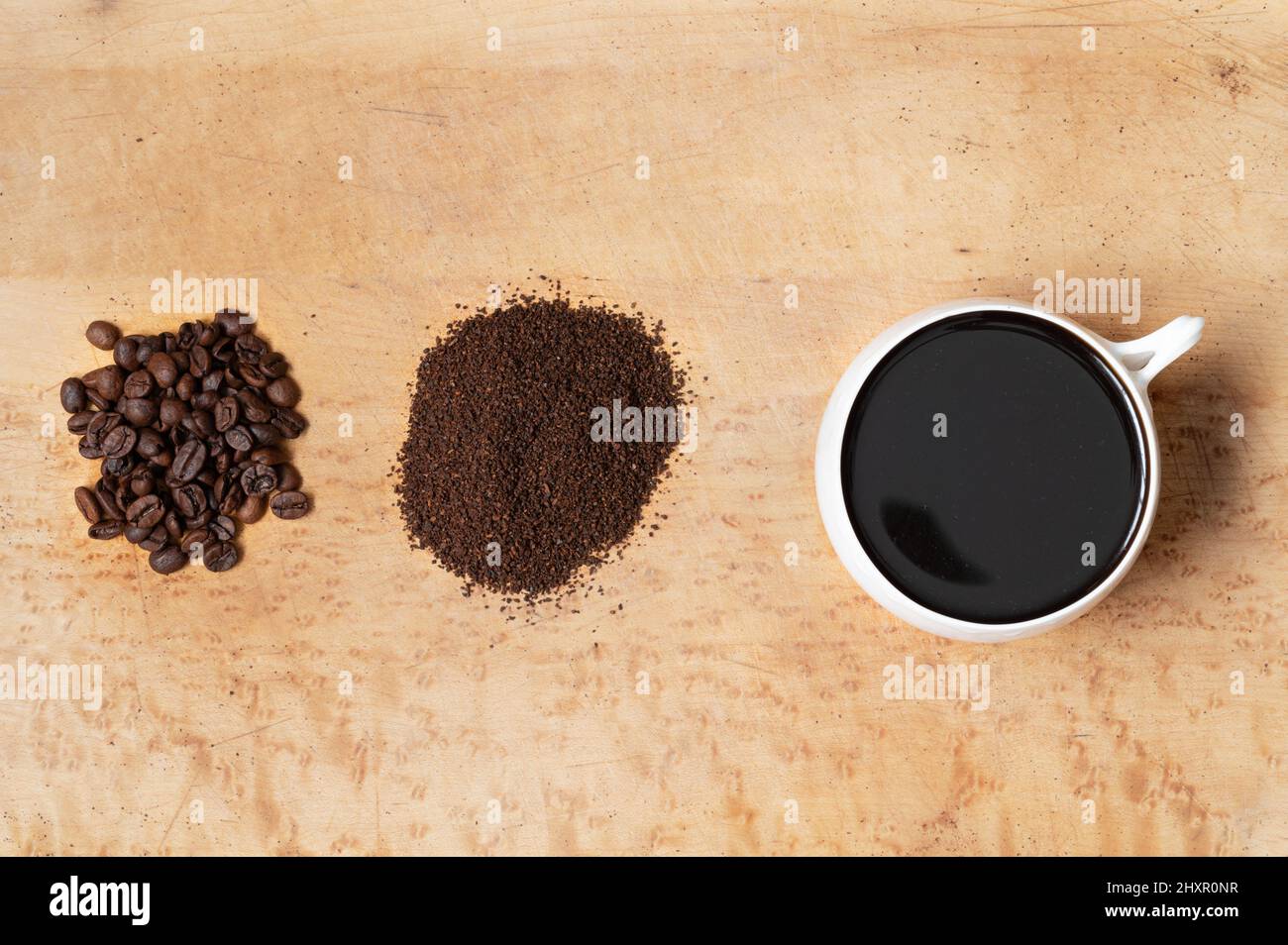 Chicchi di caffè interi, caffè macinato e una tazza di caffè nero preparato su un tavolo in legno, vista dall'alto Foto Stock