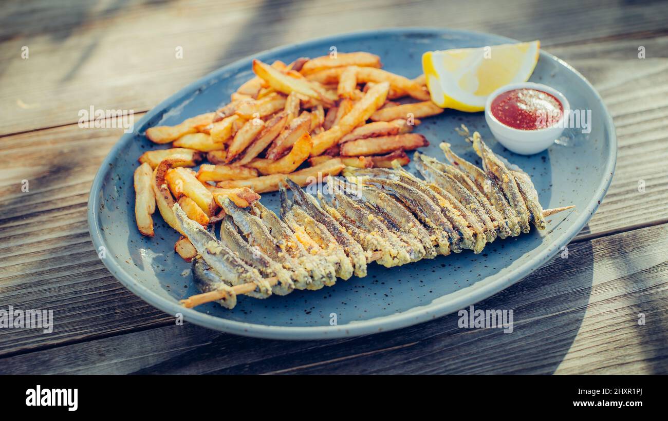 Porzione di pesce fresco e gustoso con patatine fritte su tavola di legno. Primo piano Foto Stock