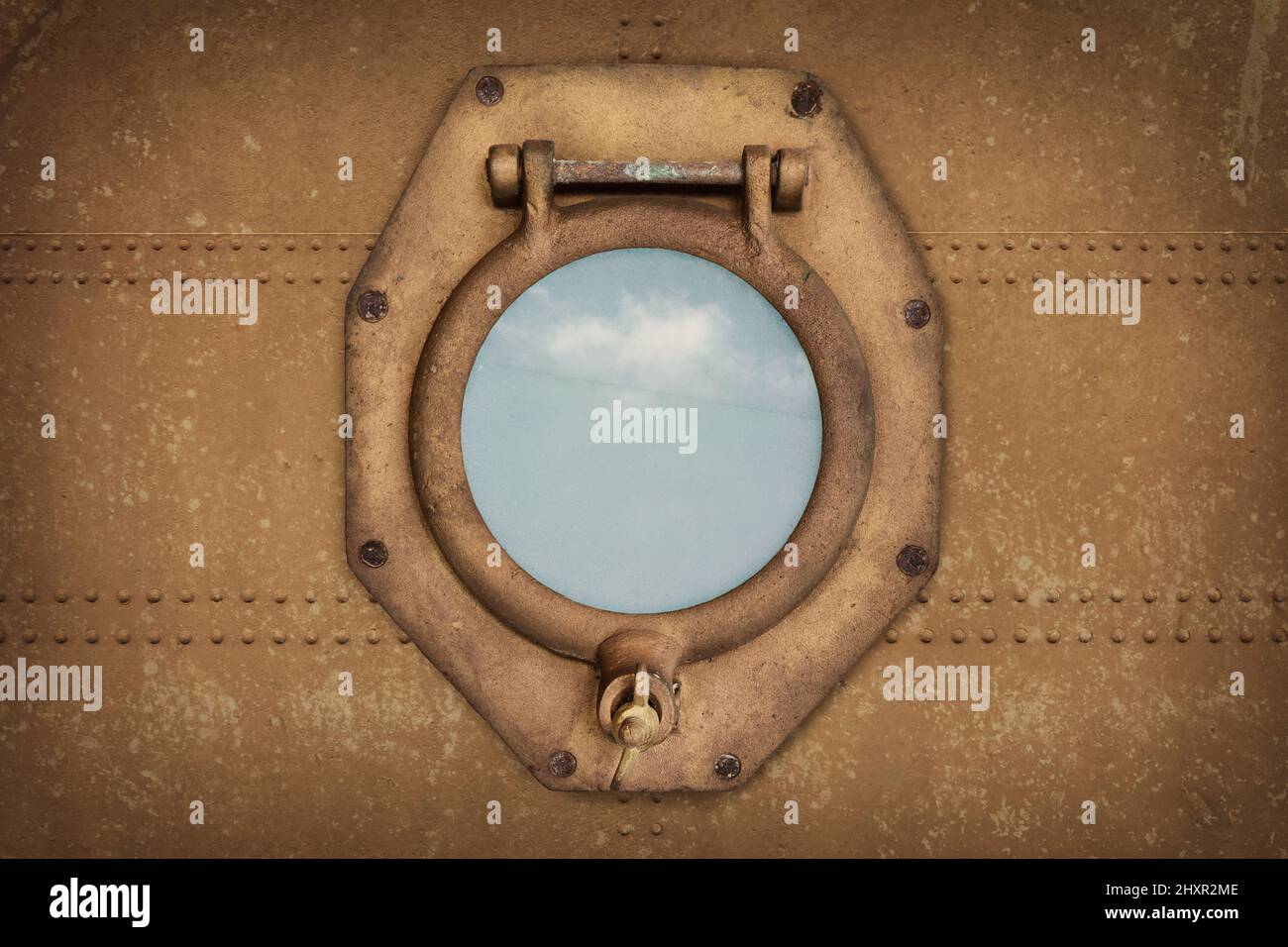 Vecchio oblò di nave arrugginito su una parete della nave con vista su un cielo blu Foto Stock