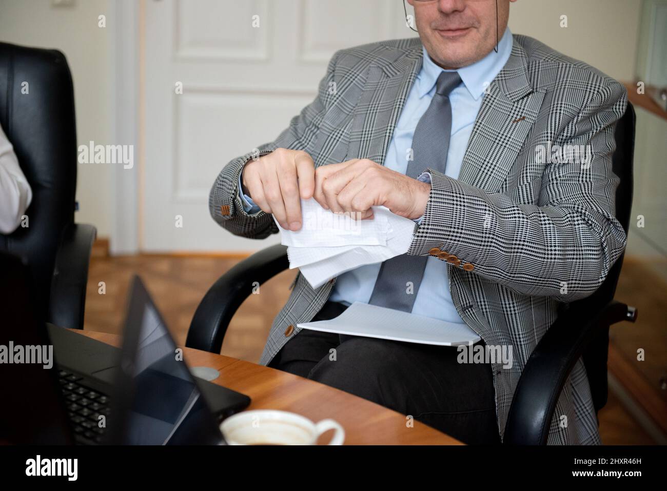 Uomo d'affari anziano seduto alla tavola rotonda e documento di strappo Foto Stock