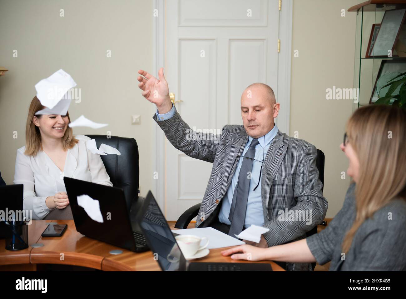 Uomo d'affari anziano seduto alla tavola rotonda e documento di strappo Foto Stock