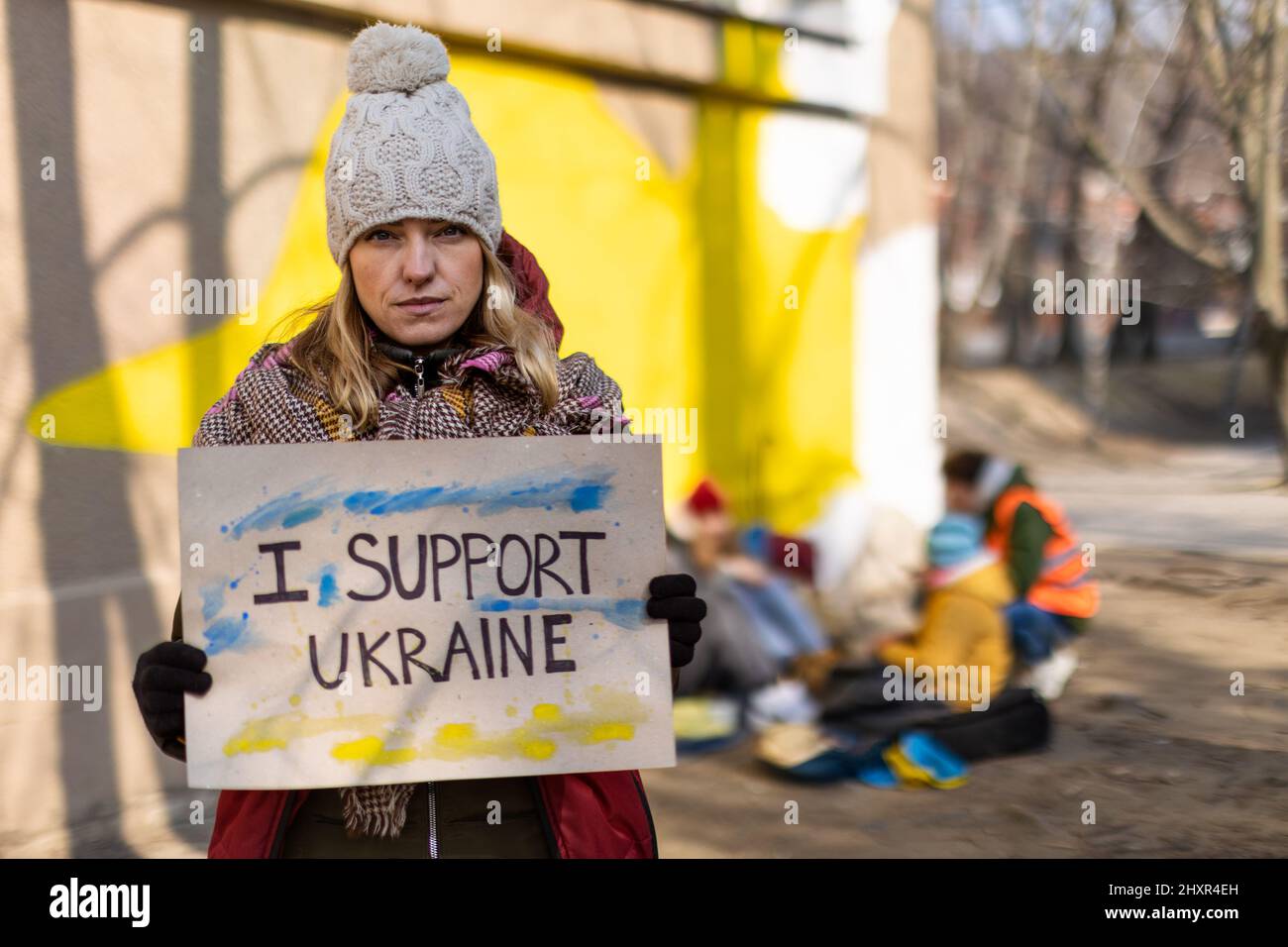 Protesta contro l'invasione russa dell'Ucraina. Donna con bandiera anti-guerra vicino al campo profughi. Foto Stock