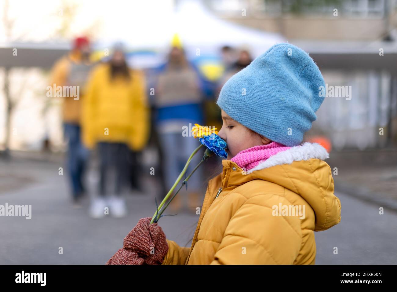 Bambina che tiene fiori gialli e blu. Protesta contro l'invasione russa dell'Ucraina. Foto Stock