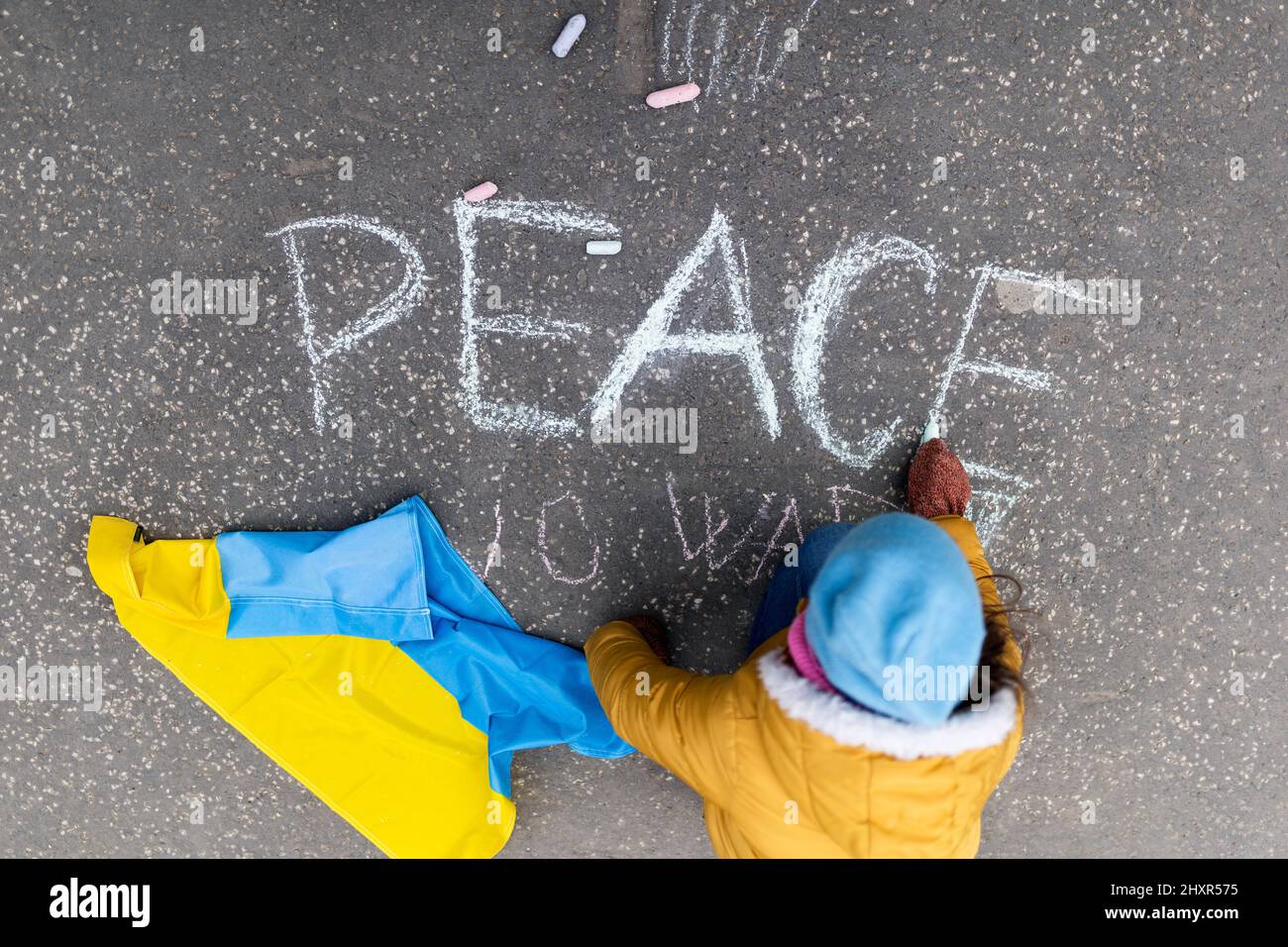 Vista dall'alto della ragazza piccola che scrive la pace con il gesso. Protesta contro l'invasione russa dell'Ucraina. Foto Stock