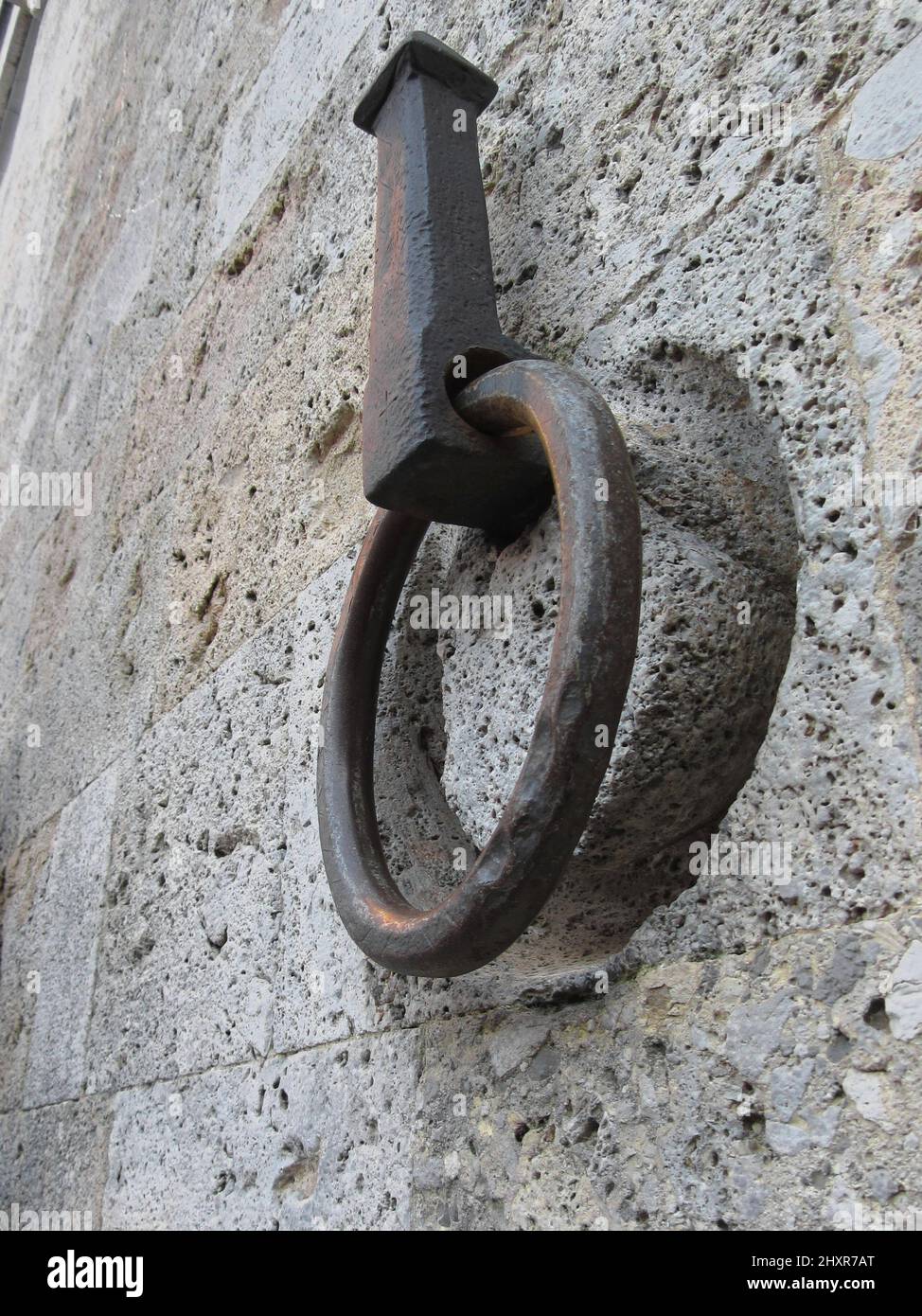 Antico cerchio di ferro appeso su un muro di pietra Foto Stock