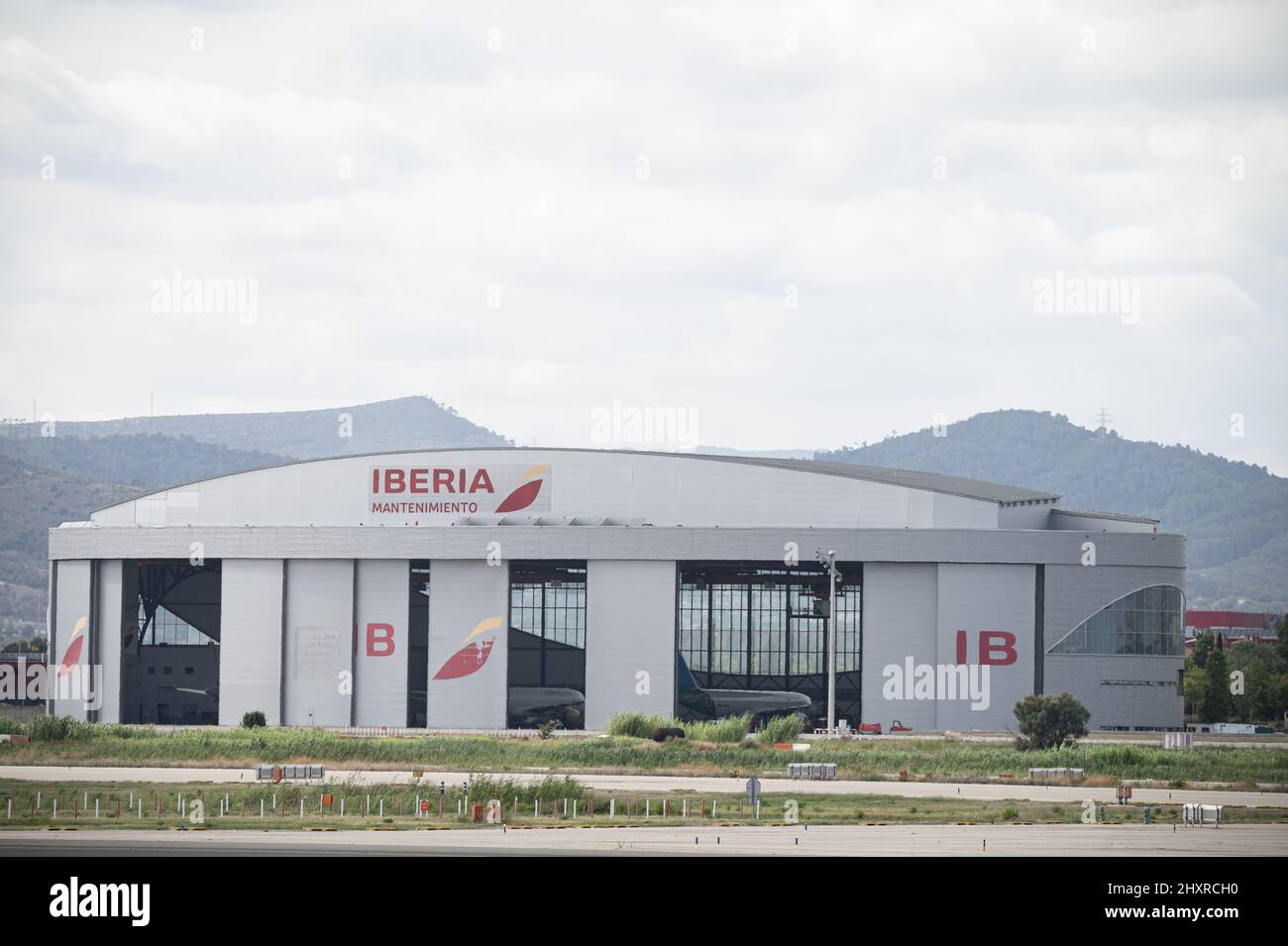 Il laboratorio di manutenzione dell'Iberia si trova all'aeroporto di Barcellona su un cielo nuvoloso Foto Stock
