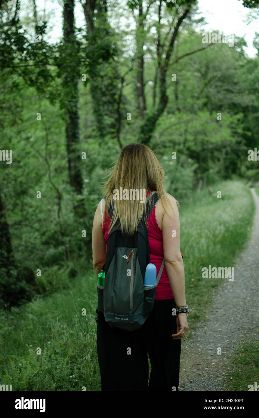 Giovane bella ragazza che cammina nella foresta girandola di nuovo alla macchina fotografica Foto Stock