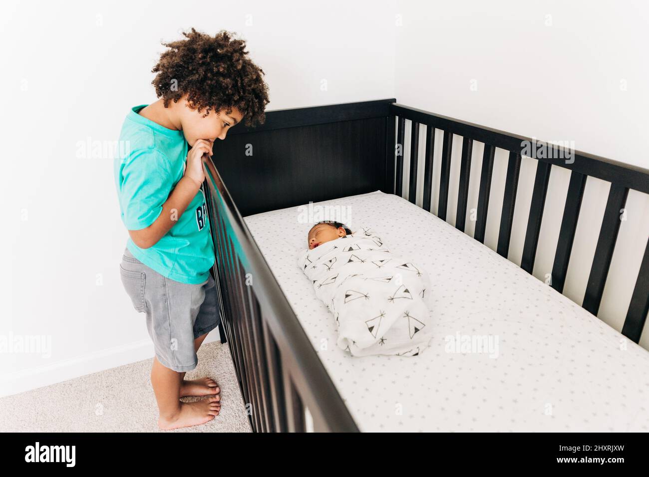 Il fratello maggiore guarda adorningly al suo fratello nuovo dormiente Foto Stock