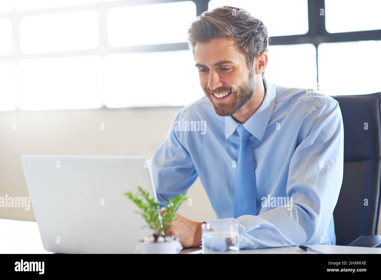 Assicurandosi che il suo profilo professionale sia aggiornato. Scatto di un giovane uomo d'affari che usa un laptop in un ufficio. Foto Stock