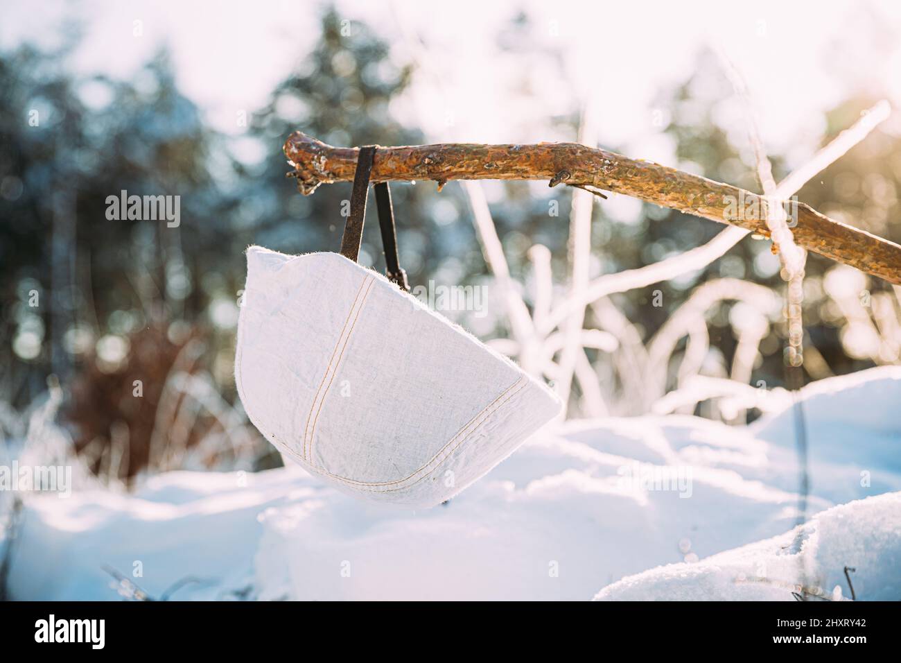 Tedesco Wehrmacht soldati fanteria casco bianco appeso su banchina di legno nella foresta invernale di neve. Seconda guerra mondiale munizioni di attrezzature dell'esercito vecchio. Metallo Foto Stock