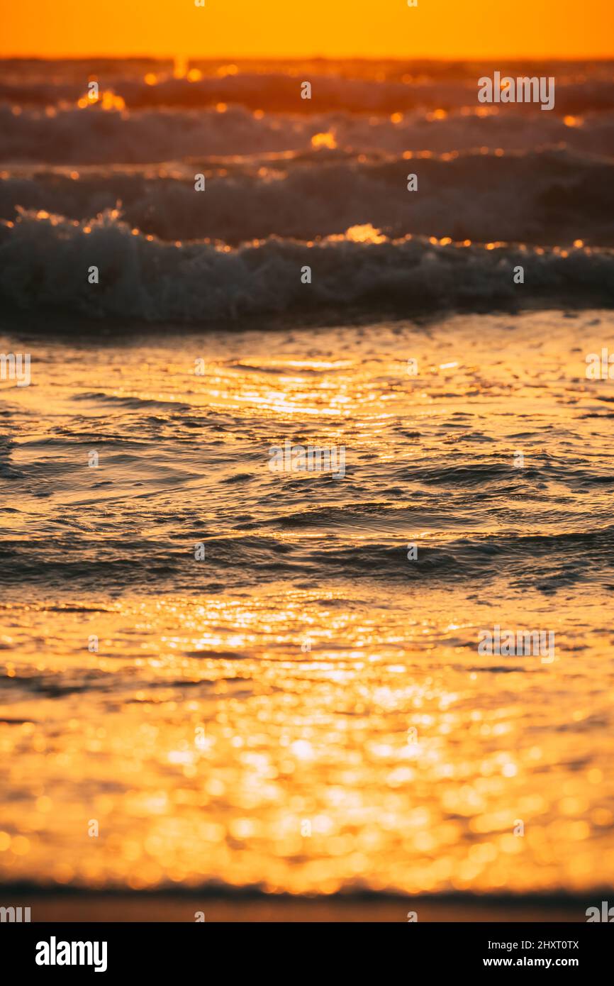 Superficie di acqua di mare al tramonto. Tramonto naturale colori caldi dell'oceano. Superficie dell'acqua marina dell'oceano con piccole onde schiumose al tramonto. Luce del sole serale Foto Stock