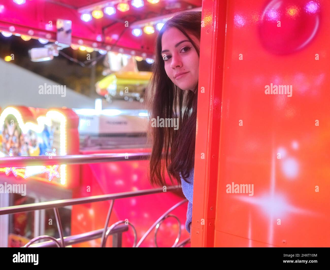 Donna che attacca la sua testa da una colonna di una fiera attrazione di notte Foto Stock