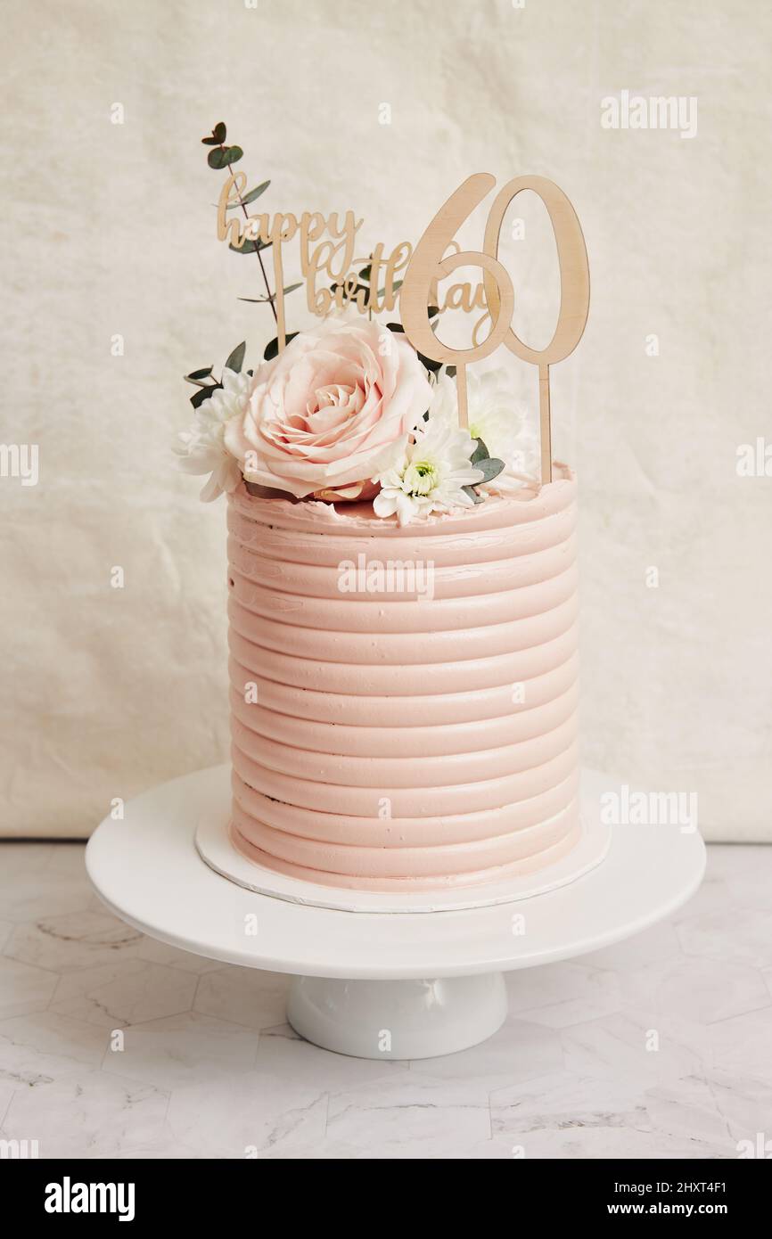 Primo piano verticale di una torta di compleanno di 60 anni su un supporto per  torte con glassa rosa chiaro Foto stock - Alamy